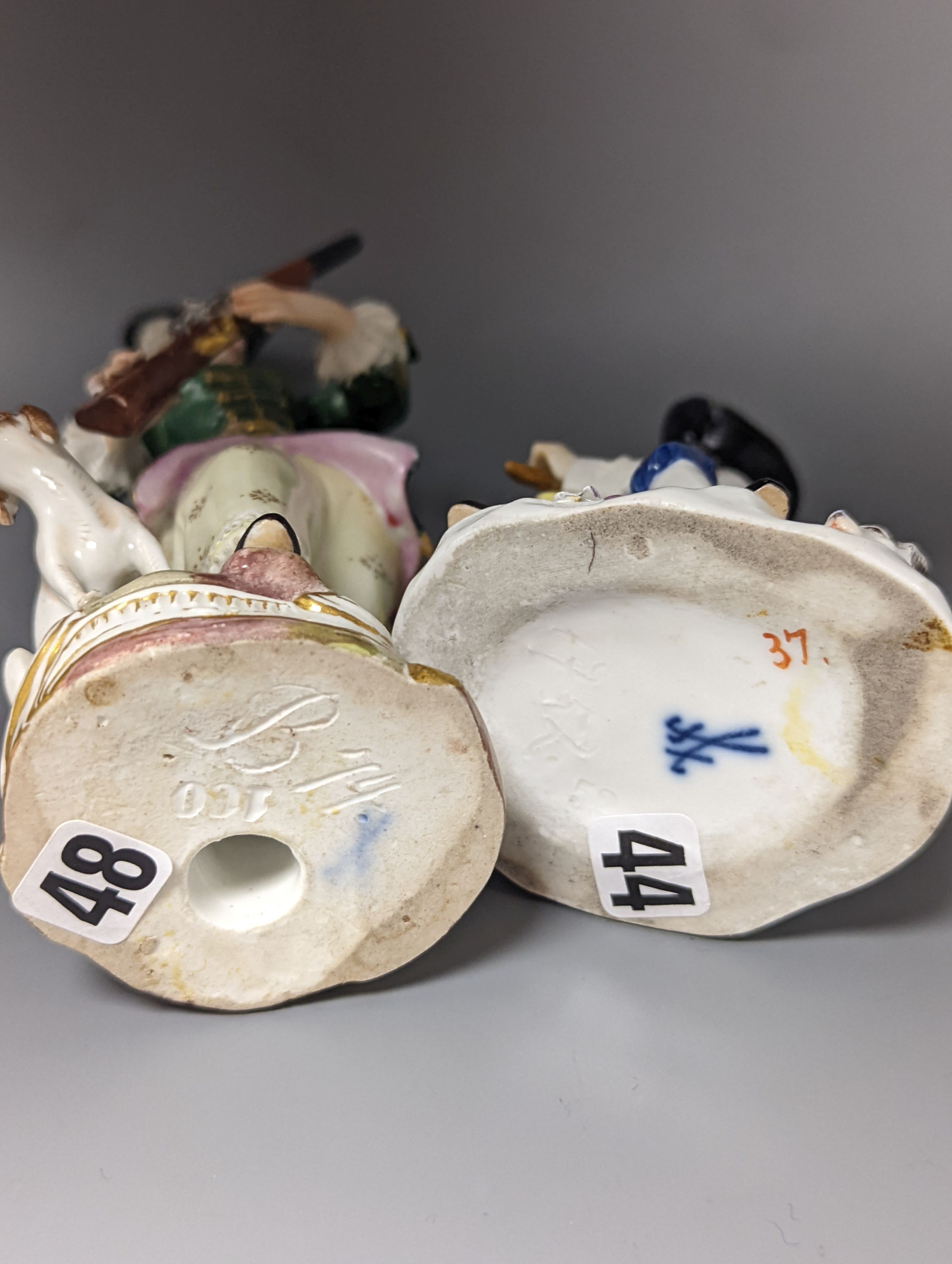 A Meissen figure of a seated man playing the bagpipes, 8.5cm., and a similar group of a huntswoman with a hound, 13cm., late 19th century, 8.5 cm and 13 cm high, some restoration